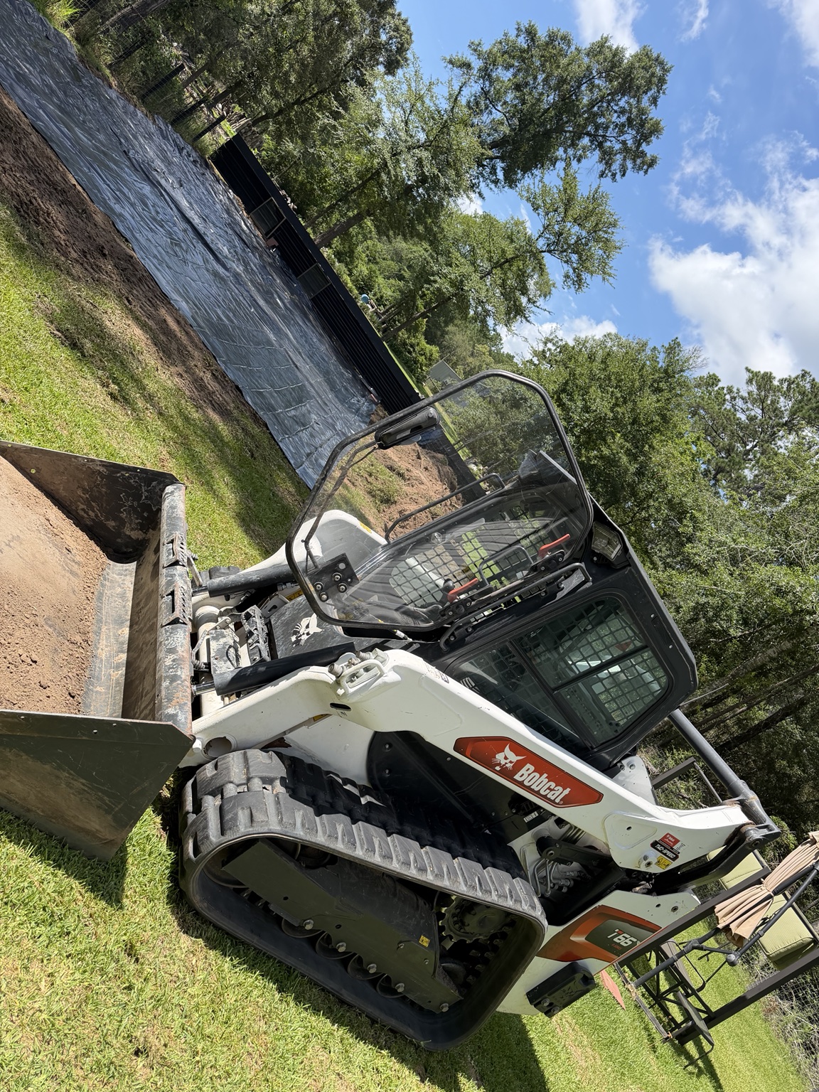 Bobcat grading land beside a prepared building pad